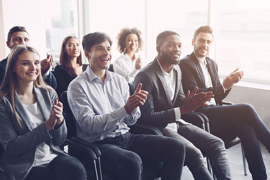 Blog - Portrait of a Group of Smiling Employees Clapping Their Hands While Sitting in a Conference Meeting in the Office