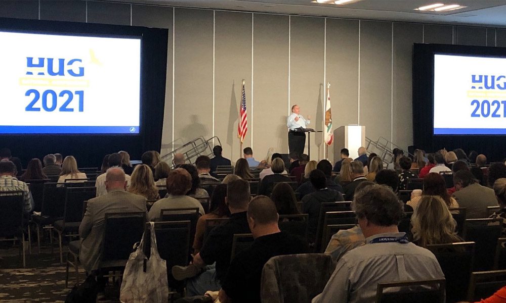 Blog - Man Presenting and Speaking in Front of Large Group of People Sitting at the 2021 HUG National Conference